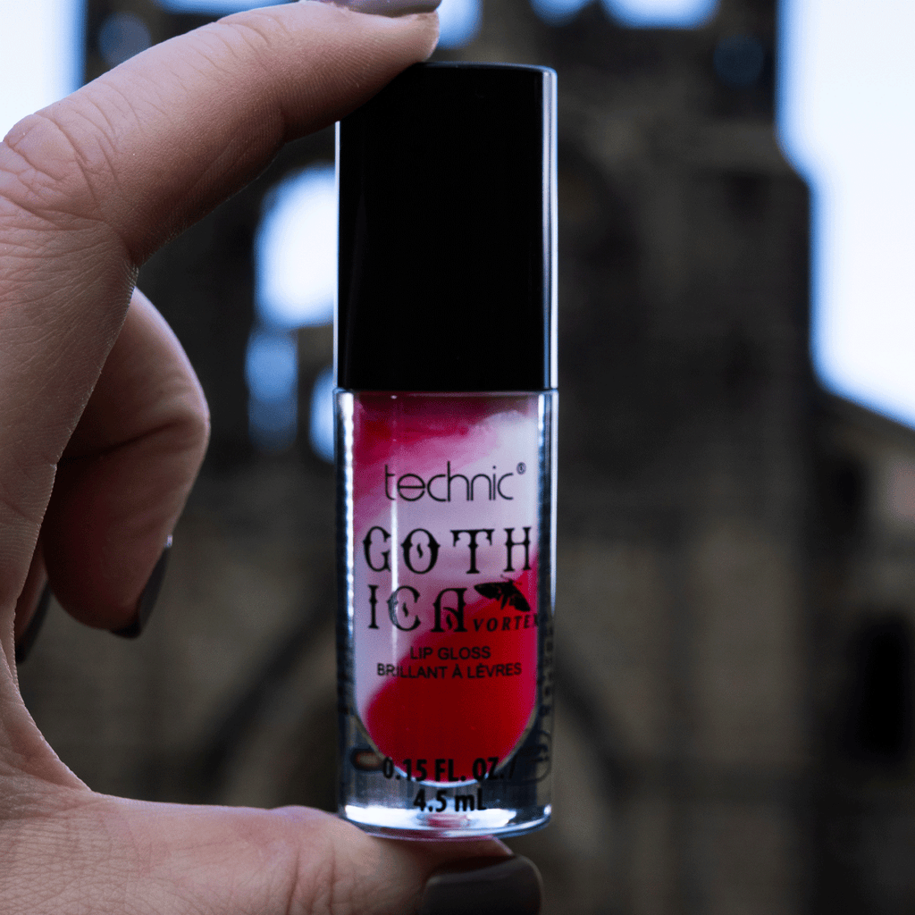 Red and white swirl lip gloss being held in front of camera in an outside setting.