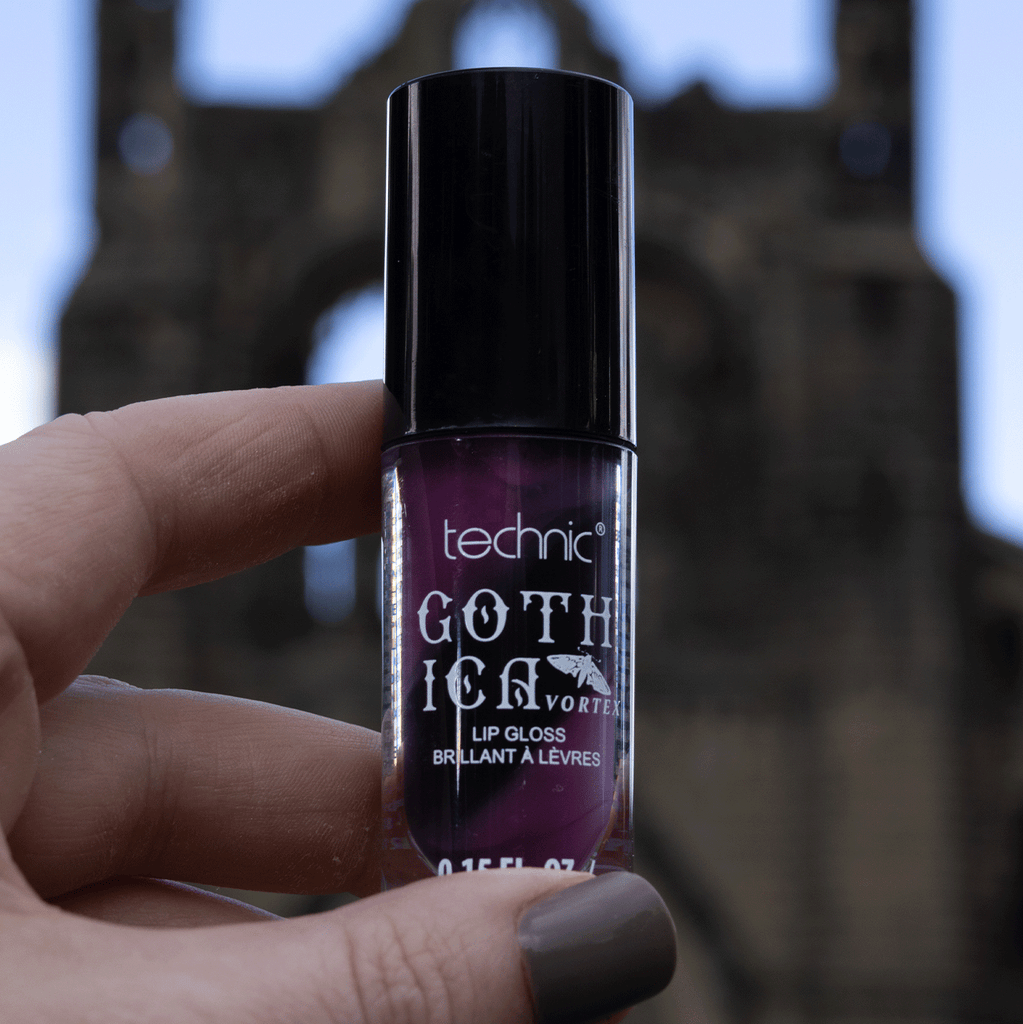Black and purple swirl lip gloss being held in front of camera in an outside setting.