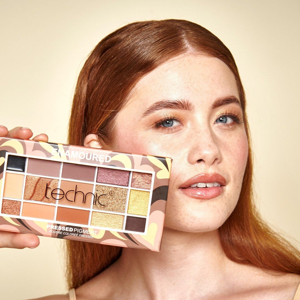 A model holding the Enamoured eyeshadow palette next to her face.