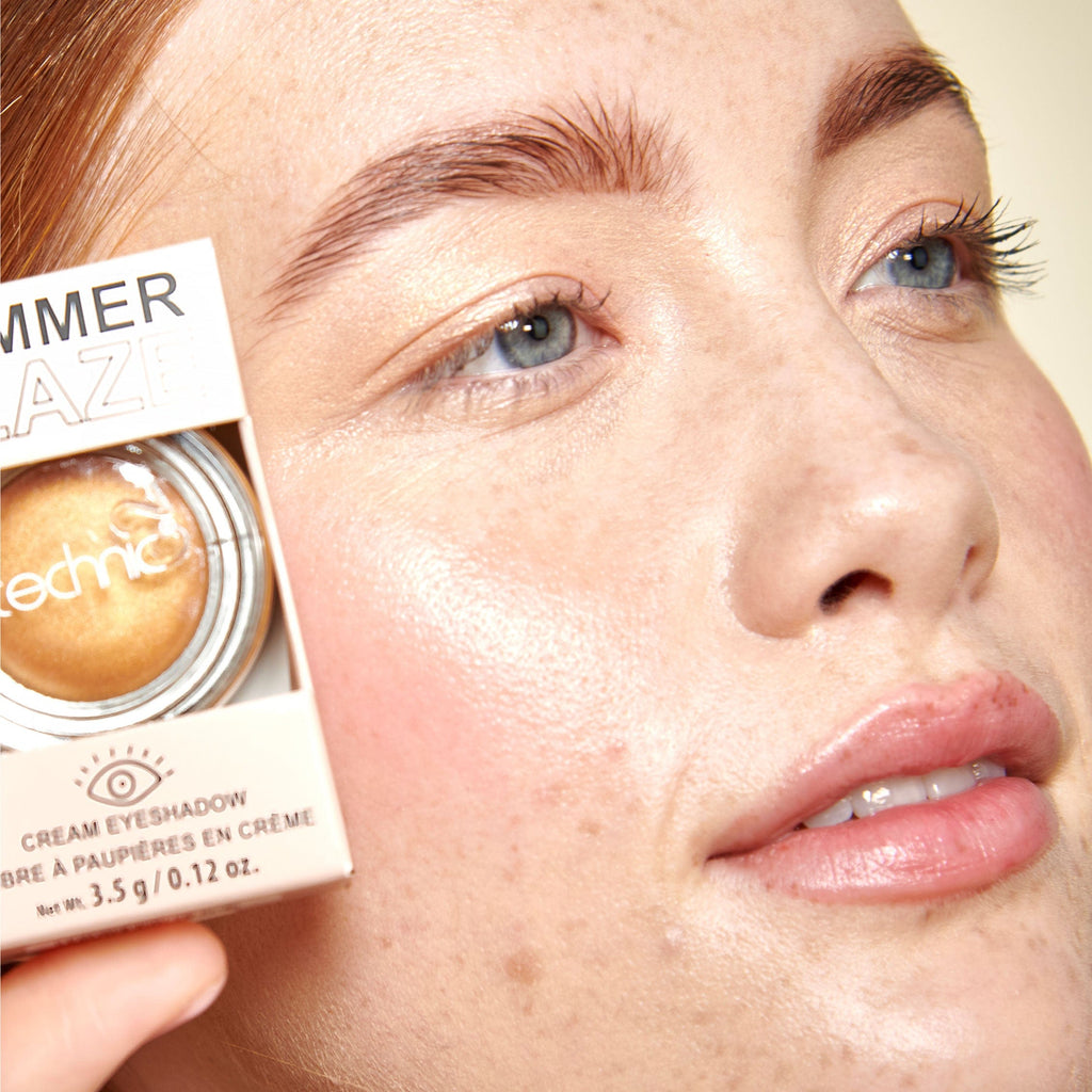Close up of a model holding the cream eyeshadow next to her face.