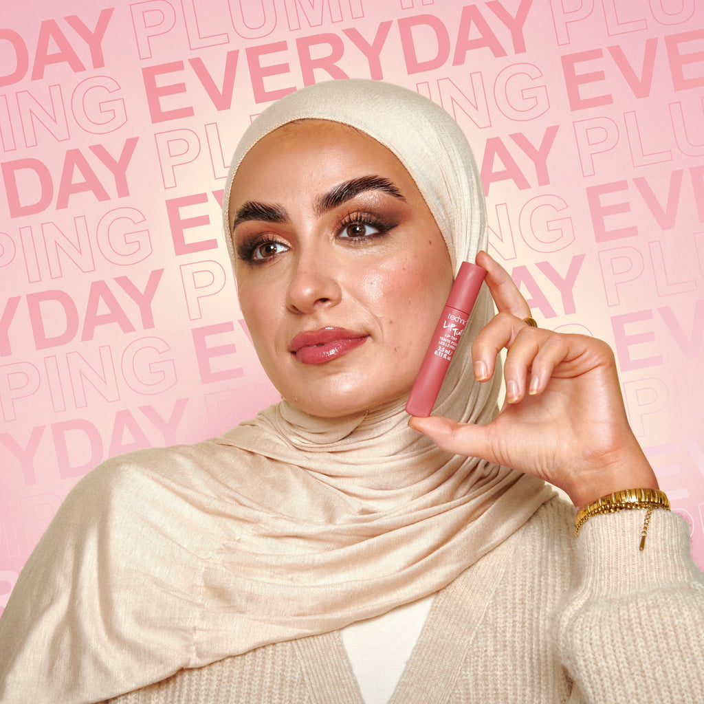 Model holding the lip tint next to her face.