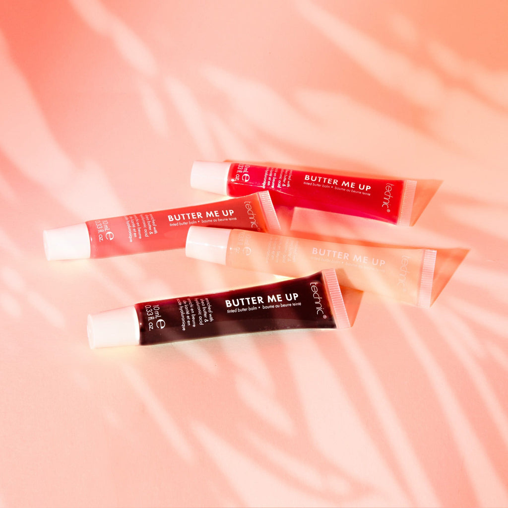 All 4 shades of the butter me up lip balm laid down on a white background with a sunset lighting effect.