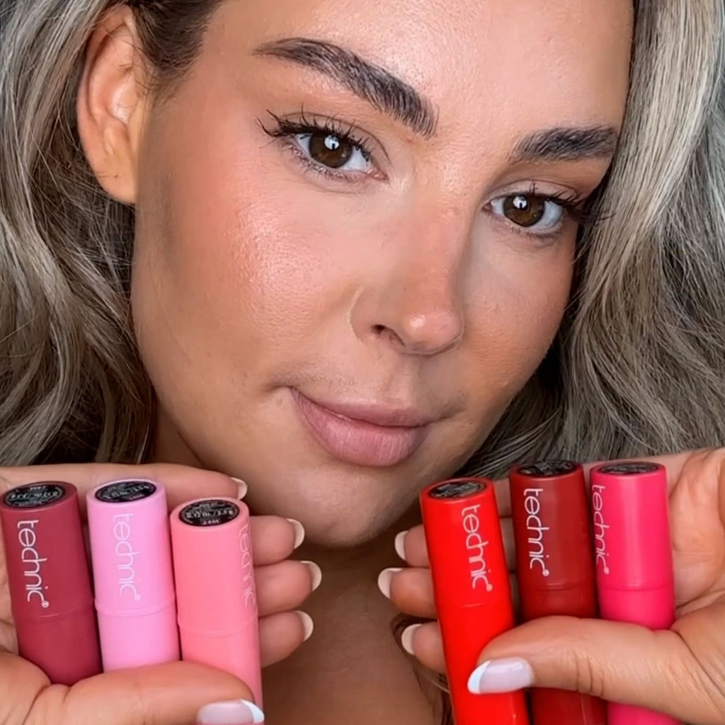 Model holding all 6 lipstick shades close to face.