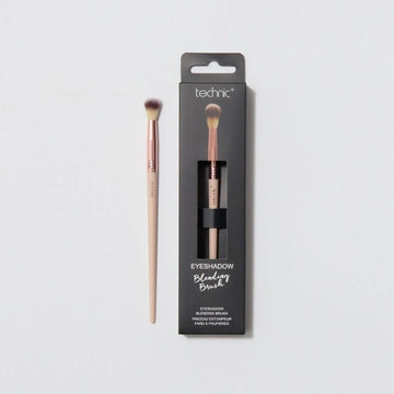 An eyeshadow blending brush in the packaging next to one out of the packaging on a white background.