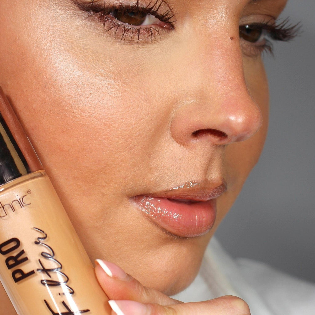 A close up of a model with the pro filter applied to her face while holding the product next to her face.